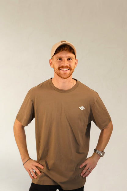 Man wearing a brown t-shirt with a logo on a plain background