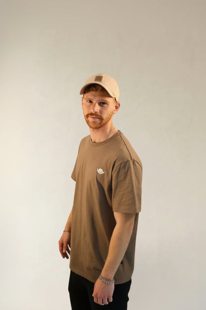 Man wearing a brown t-shirt and cap against a plain background