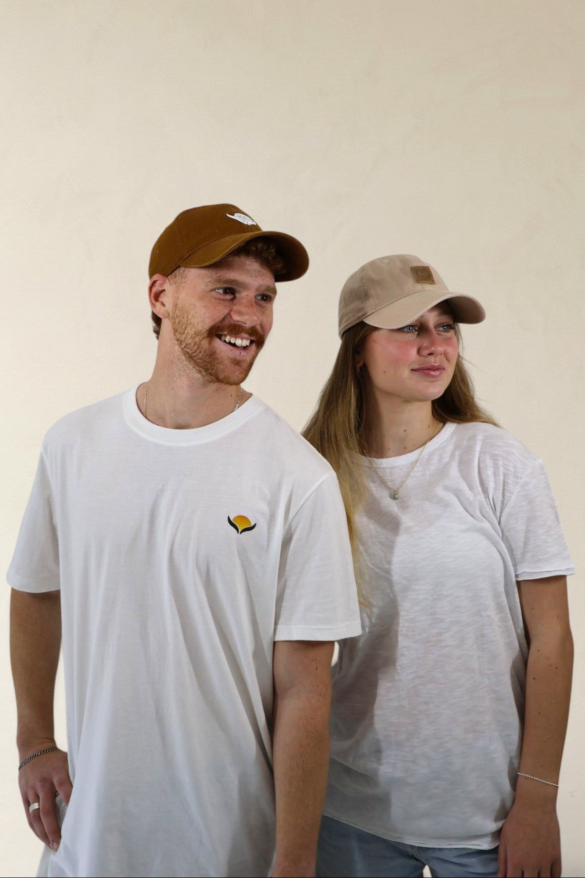 Two people wearing white t-shirts with a small logo, standing against a plain background.