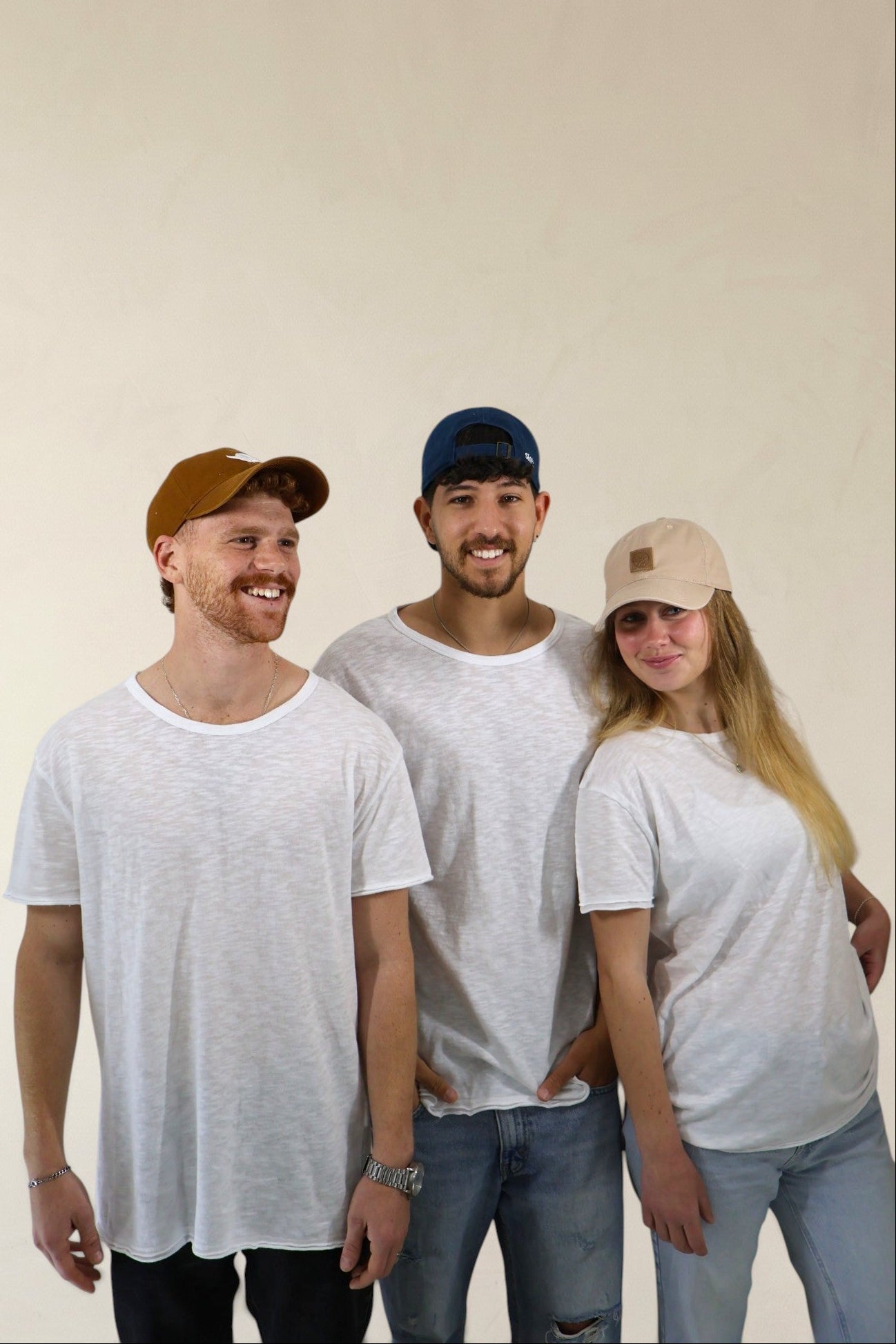 Three people wearing white t-shirts and casual clothing against a plain background