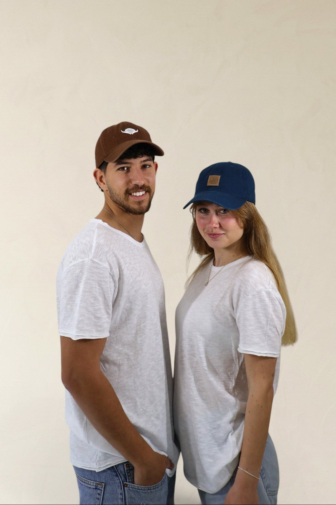 Two people wearing gray t-shirts and baseball caps against a plain background