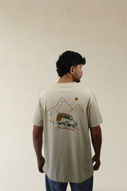 Man wearing a beige t-shirt with a graphic design on the back, standing against a plain background