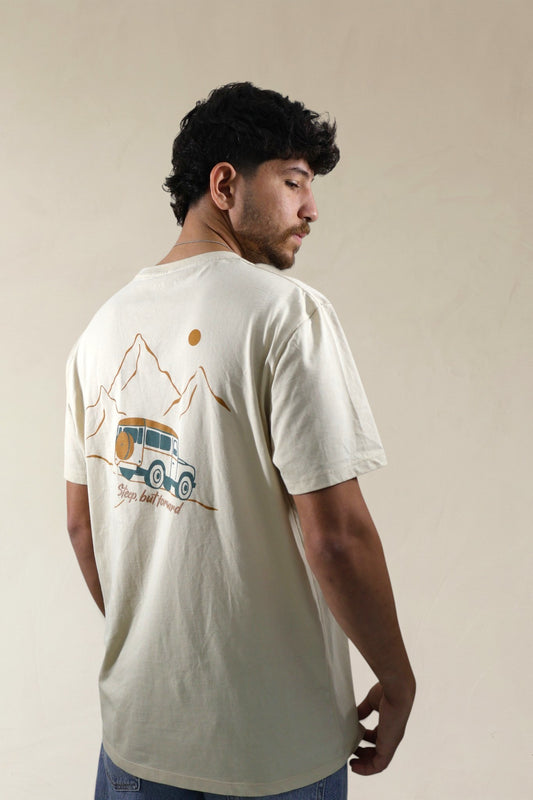 Man wearing a cream t-shirt with a graphic design on the back against a beige background