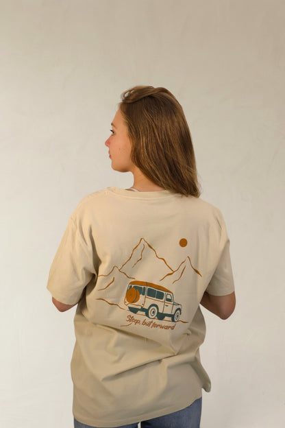 Person wearing a beige t-shirt with a graphic design on the back